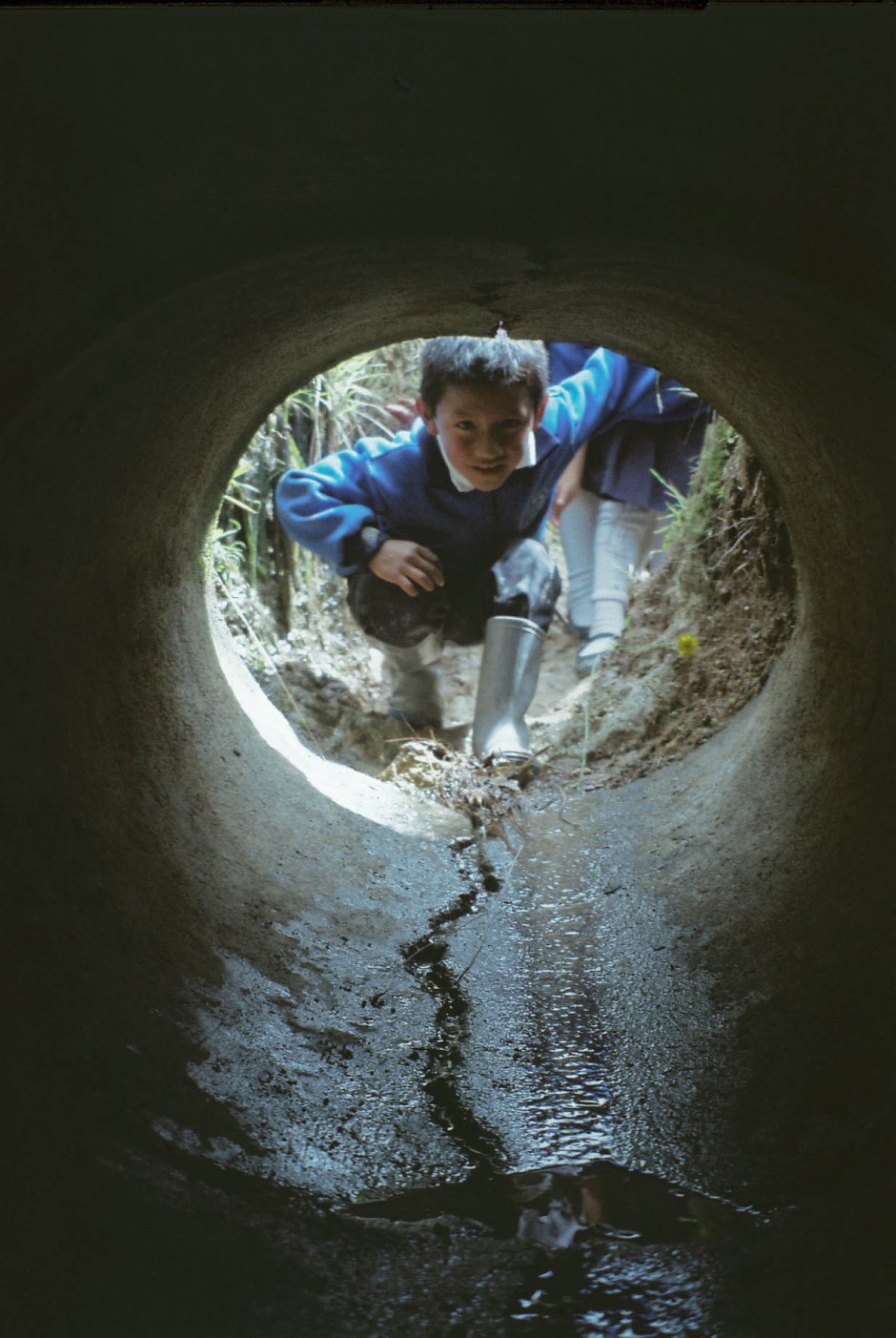 A boy looks through a túnel secreto that runs underneath a road connecting their school to the corn farm on the other side. Chilca Totora, Ecuador.